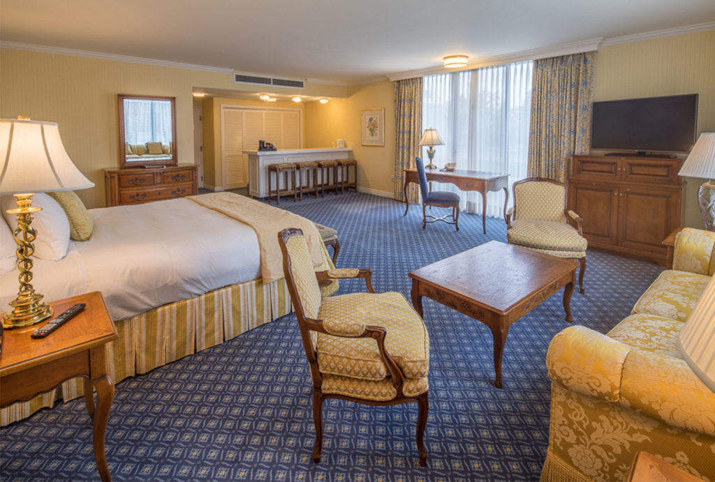 The Executive King Suite guest room at the Little America Hotel in Cheyenne, Wyoming with a spacious bathroom, work desk, and a separate seating area.