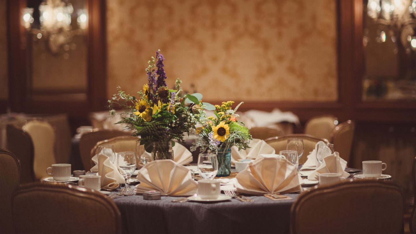 Wedding dinner table set up with napkins, table settings, and floral centerpiece.