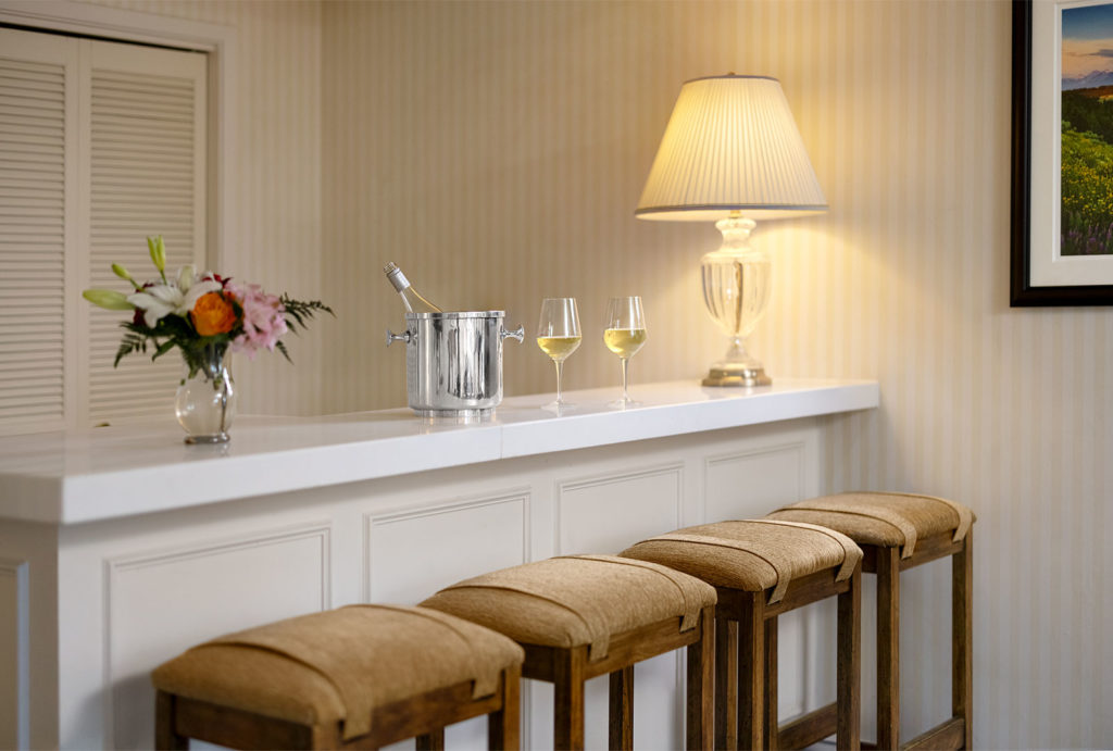 In-room bar with four stools and two wine glasses on the marble counter.