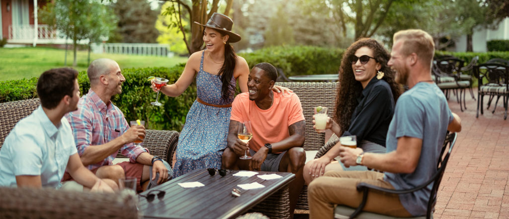 A group of six friends sitting around a table with drinks in hand on Hathaway's outdoor patio.