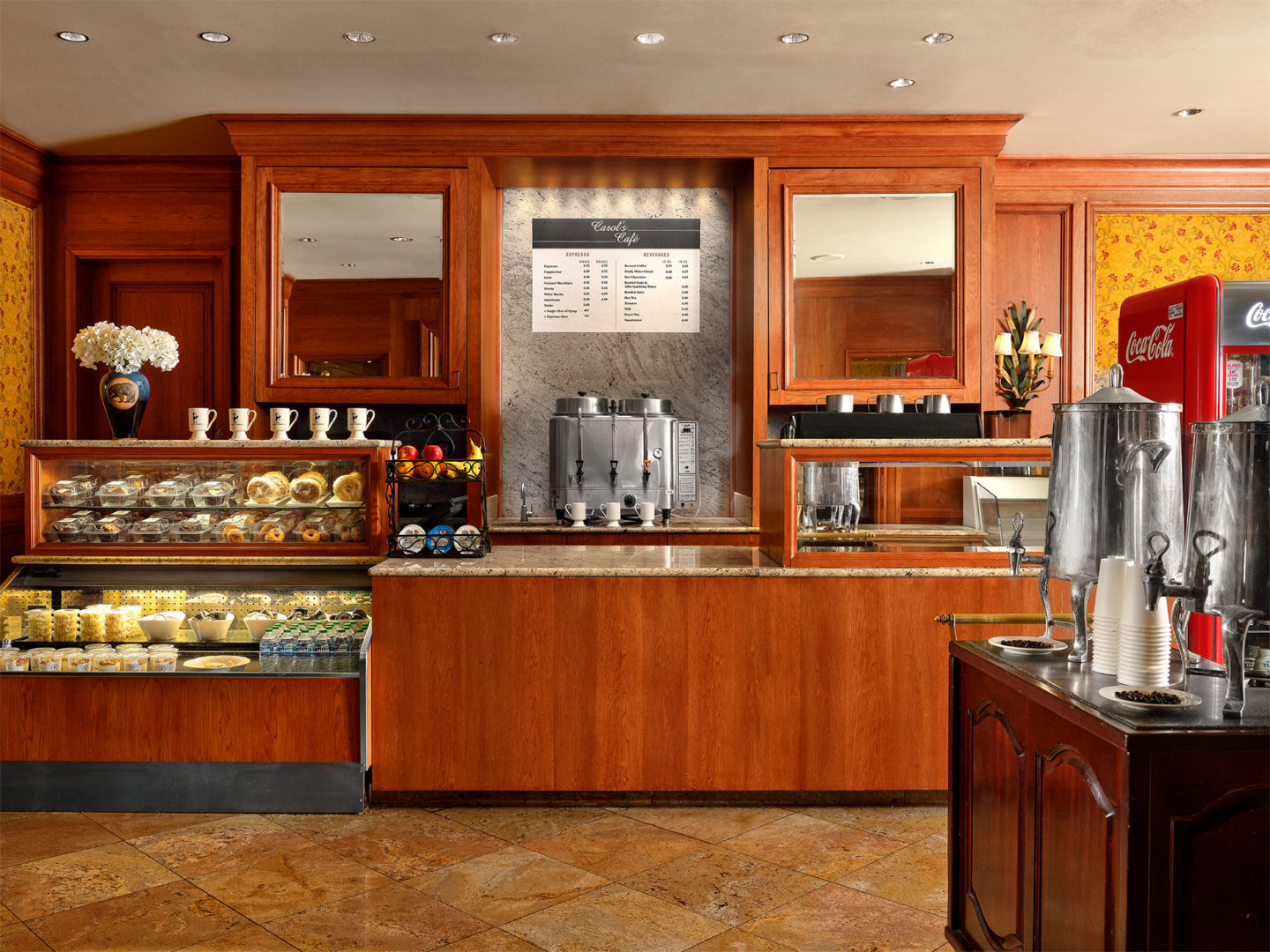 Carol's Cafe with a pastry display, espresso and coffee makers and counter for guests to buy foo and drinks.