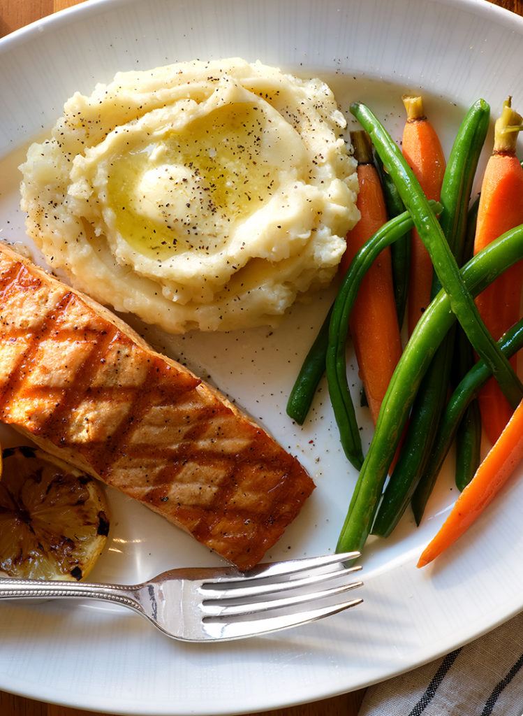 Close up of Salmon, mashed potatoes, and beans and carrots.