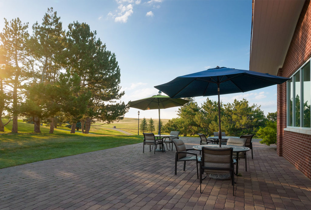 Patio area with umbrella tables and chairs overlooking the Little America Cheyenne Golf Course.