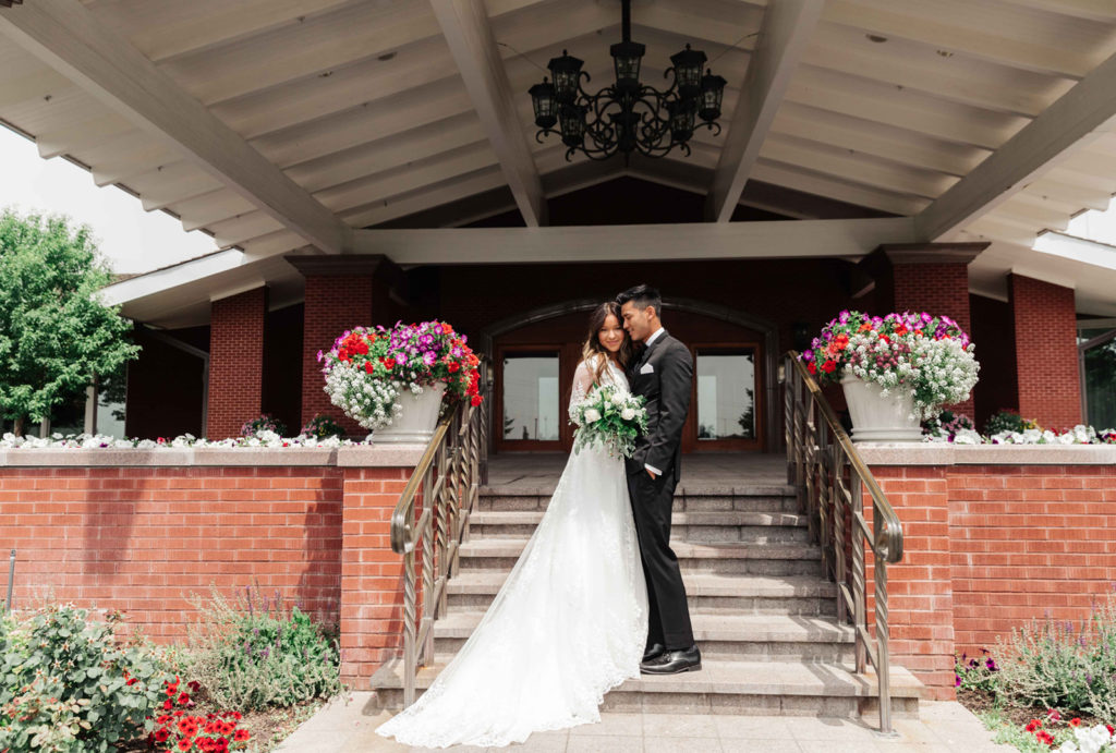A bride and groom posing on the stairs leading into the entrance of Little America Cheyenne.