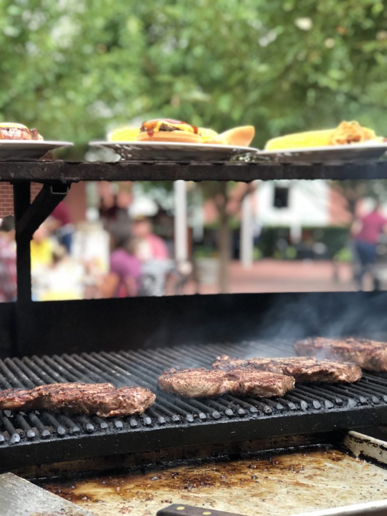 A picture of burgers and steaks on the grill