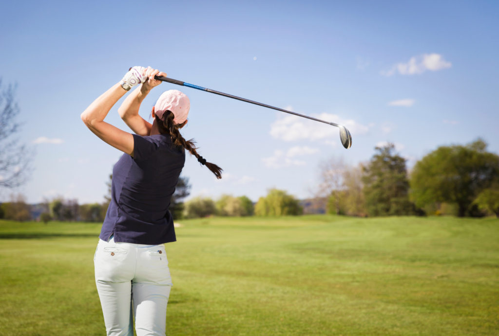 Woman swinging a golf club.